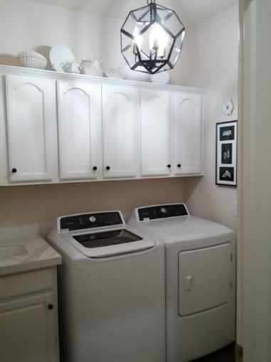 clothes washing area with a chandelier, cabinets, and separate washer and dryer