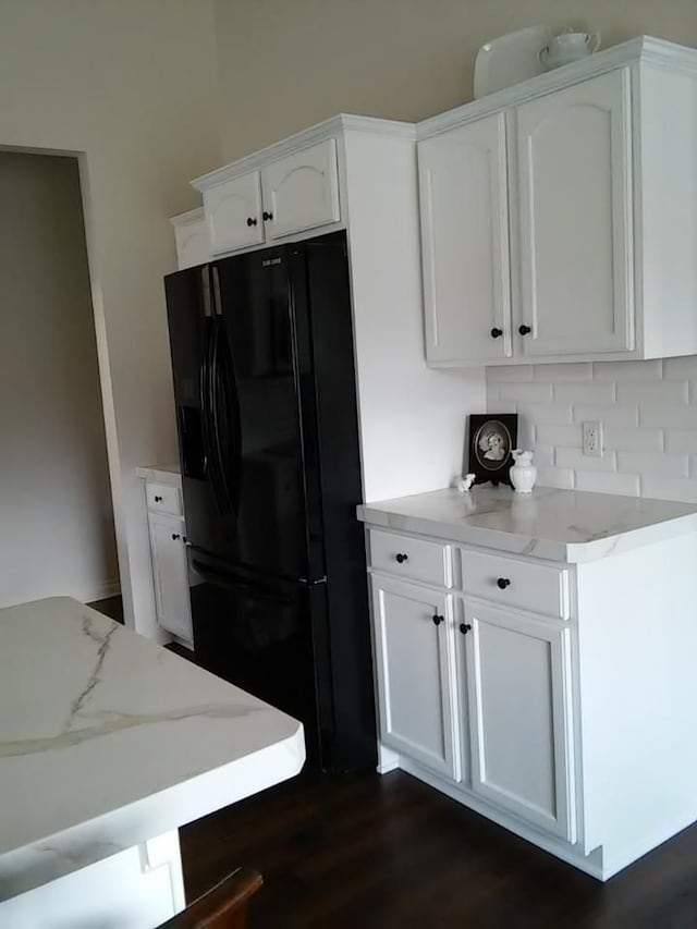 kitchen with white cabinetry, light stone countertops, dark wood-type flooring, and black refrigerator with ice dispenser