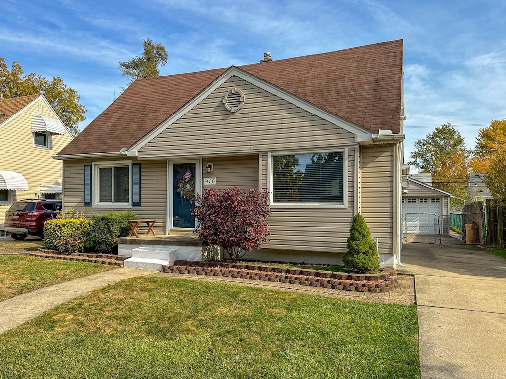 view of front of home featuring a garage, concrete driveway, a shingled roof, and a front yard