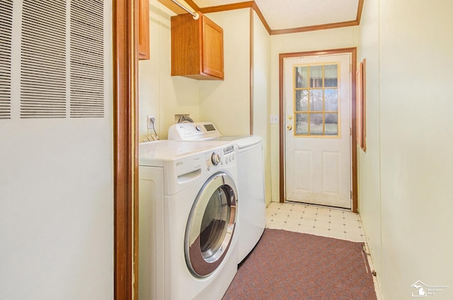 clothes washing area with crown molding, cabinets, and washer and clothes dryer