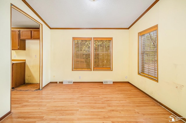 empty room with ornamental molding, a textured ceiling, and light wood-type flooring