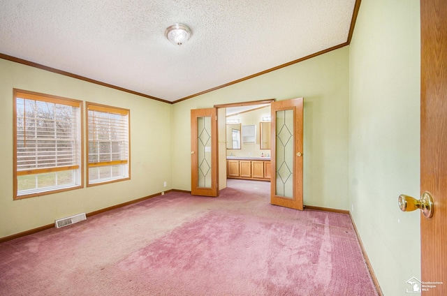 carpeted spare room featuring lofted ceiling, ornamental molding, and a textured ceiling