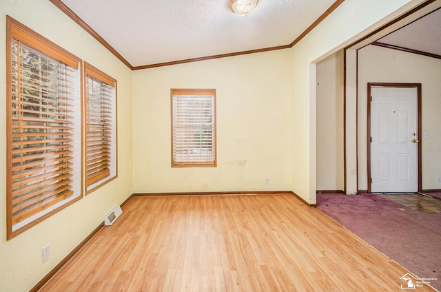 empty room featuring lofted ceiling, crown molding, light hardwood / wood-style flooring, and a textured ceiling