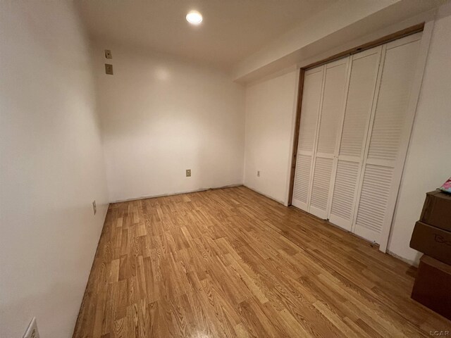 unfurnished bedroom with light wood-type flooring and a closet