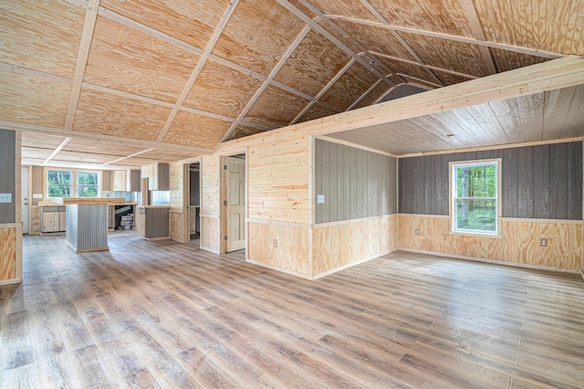 unfurnished living room with lofted ceiling, hardwood / wood-style floors, and wood walls