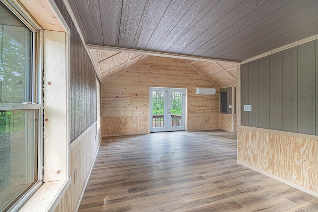 additional living space featuring an AC wall unit, hardwood / wood-style floors, wooden walls, wooden ceiling, and french doors