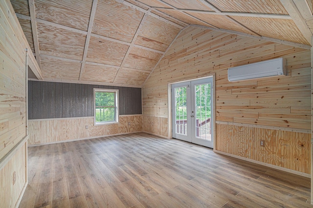 unfurnished room with wood-type flooring, vaulted ceiling, a wall unit AC, and wood walls