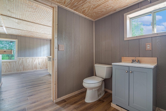 bathroom featuring hardwood / wood-style floors, wood walls, vanity, toilet, and wooden ceiling