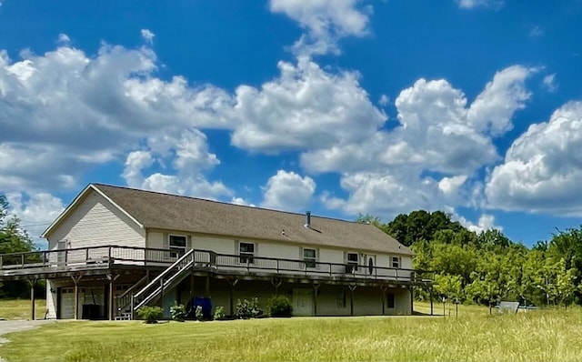 rear view of house featuring a wooden deck and a yard