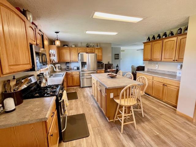 kitchen featuring a kitchen island, decorative light fixtures, sink, a breakfast bar area, and stainless steel appliances