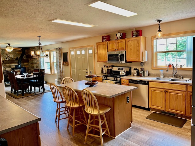 kitchen featuring a kitchen island, appliances with stainless steel finishes, pendant lighting, sink, and a healthy amount of sunlight