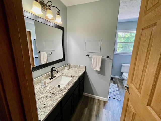 bathroom featuring hardwood / wood-style flooring, vanity, toilet, and a textured ceiling