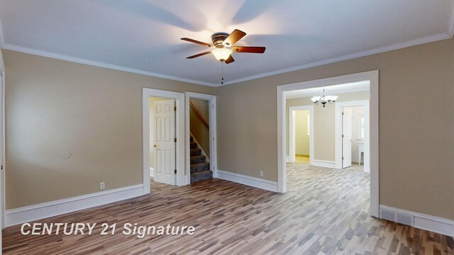 empty room with ornamental molding, ceiling fan with notable chandelier, and hardwood / wood-style floors