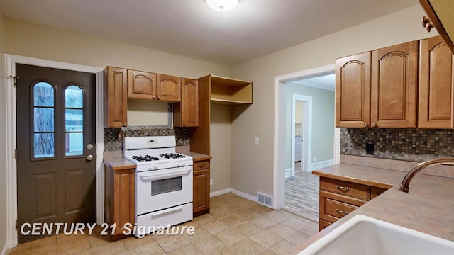 kitchen with tasteful backsplash, white gas range, and light tile patterned floors