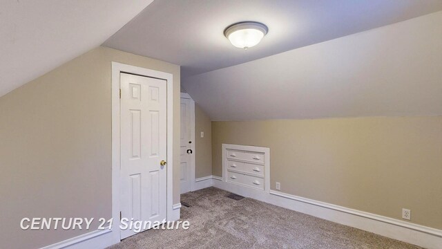 additional living space featuring vaulted ceiling and carpet flooring