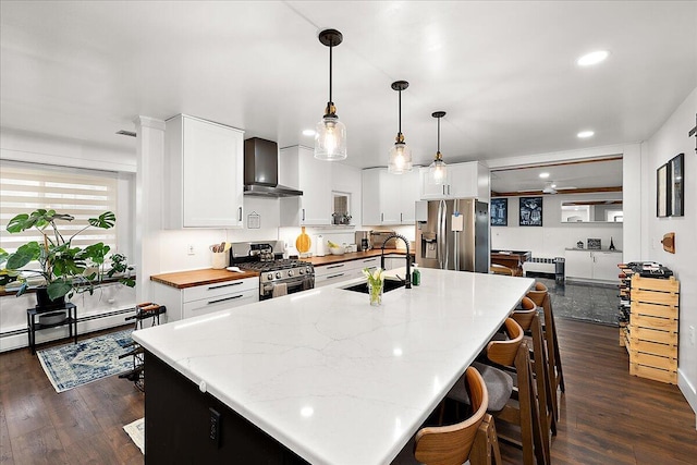 kitchen with sink, wall chimney exhaust hood, stainless steel appliances, and white cabinetry