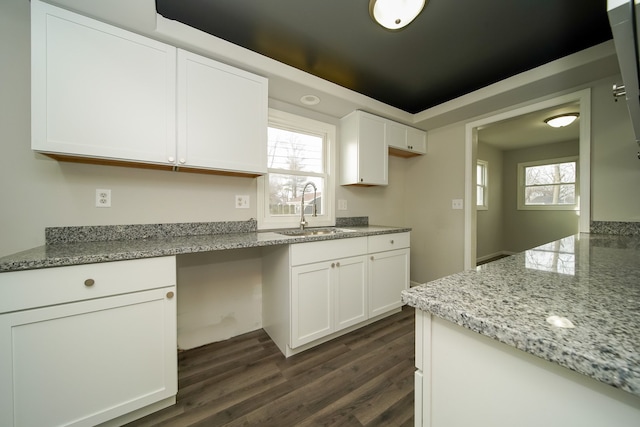 kitchen featuring dark wood-type flooring, sink, plenty of natural light, light stone countertops, and white cabinets