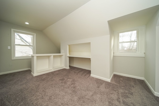 additional living space featuring vaulted ceiling and carpet flooring