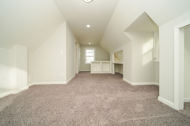 bonus room with vaulted ceiling and light colored carpet