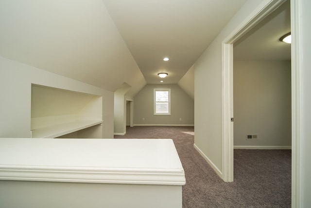 additional living space with lofted ceiling and dark colored carpet