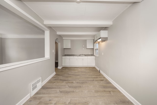 corridor with beamed ceiling and light hardwood / wood-style flooring