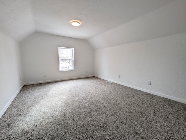 additional living space featuring lofted ceiling, a textured ceiling, and carpet