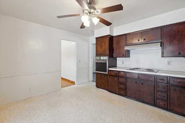 kitchen featuring ceiling fan, stainless steel oven, dark brown cabinetry, and white cooktop