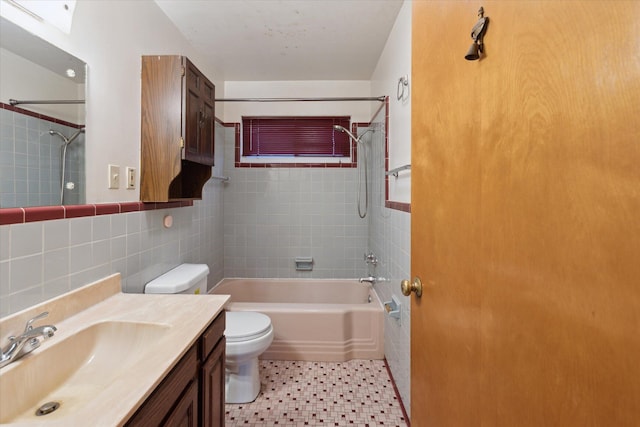 full bathroom featuring tile walls, vanity, tiled shower / bath, and toilet