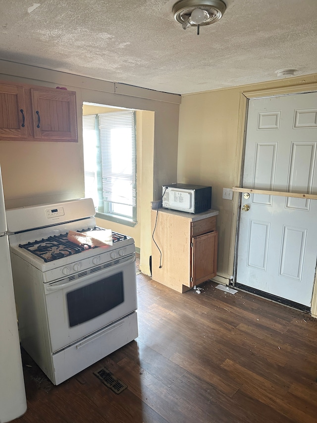 kitchen with dark hardwood / wood-style floors, white gas range, and a textured ceiling