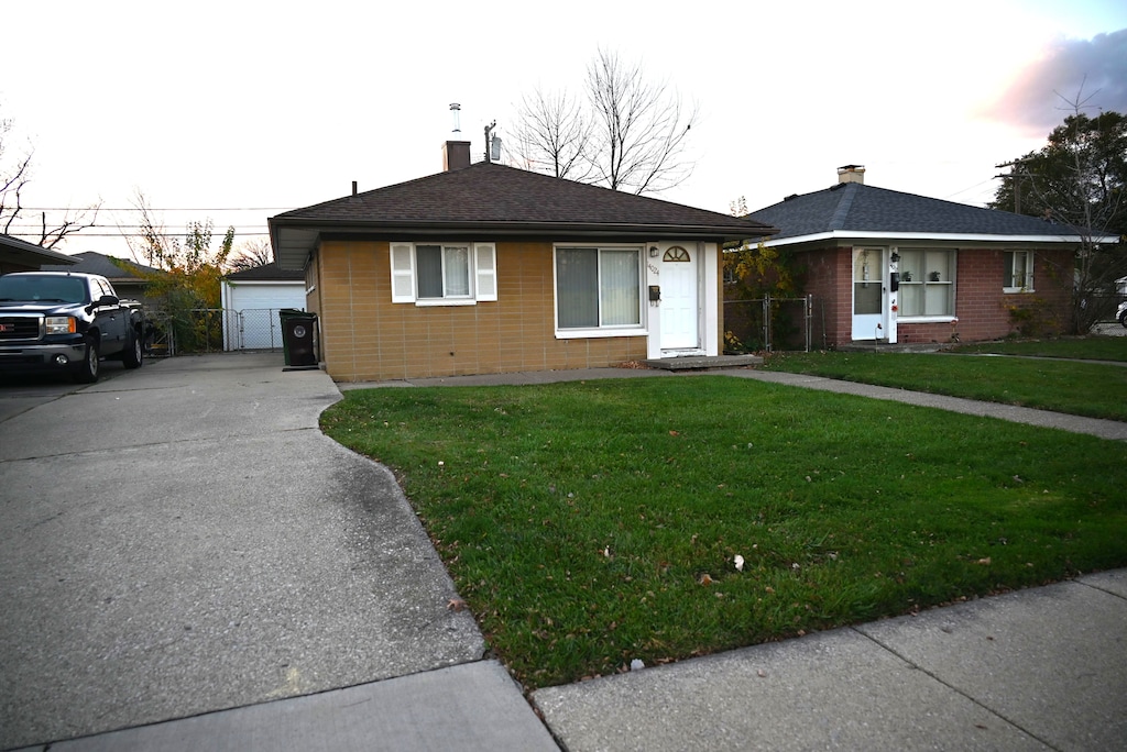 view of front of home with a garage, an outdoor structure, and a front lawn