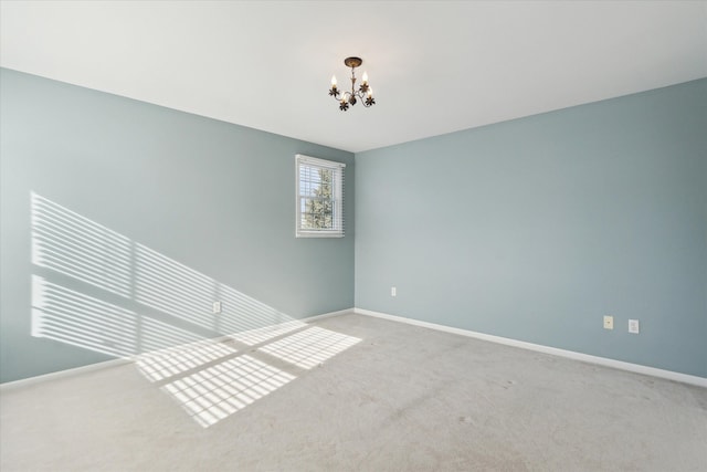 carpeted empty room with an inviting chandelier