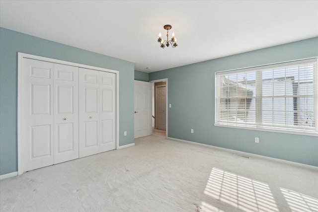 unfurnished bedroom with light colored carpet, a closet, and a chandelier