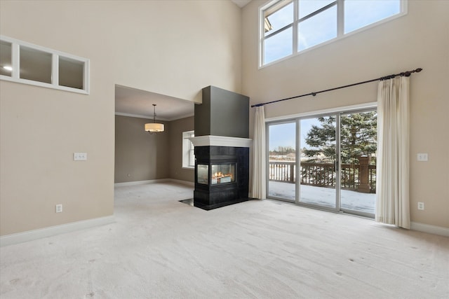 unfurnished living room with carpet flooring, crown molding, plenty of natural light, and a multi sided fireplace