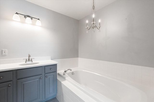 bathroom with vanity, a notable chandelier, and tiled bath