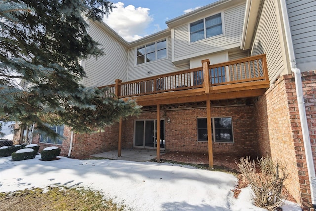 snow covered back of property featuring a patio area