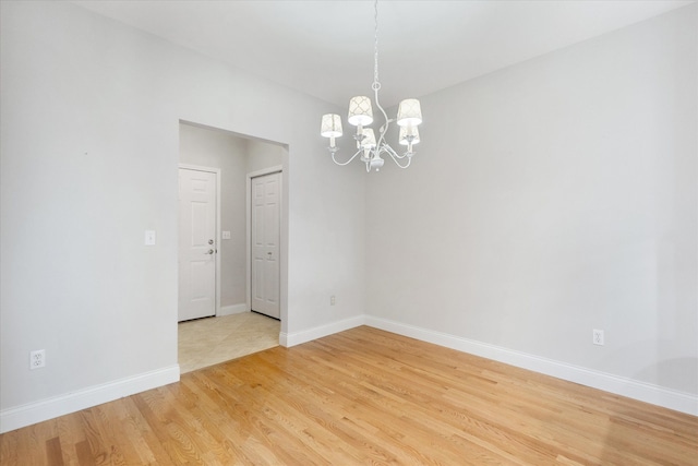 spare room with hardwood / wood-style floors and a notable chandelier