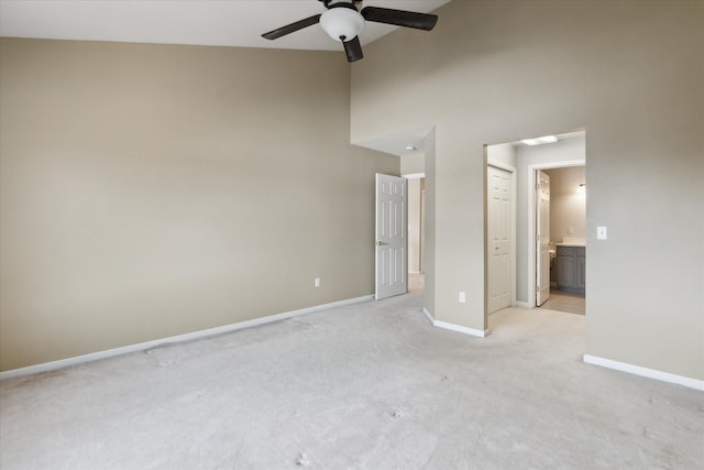 unfurnished bedroom featuring ceiling fan, a towering ceiling, connected bathroom, and light carpet