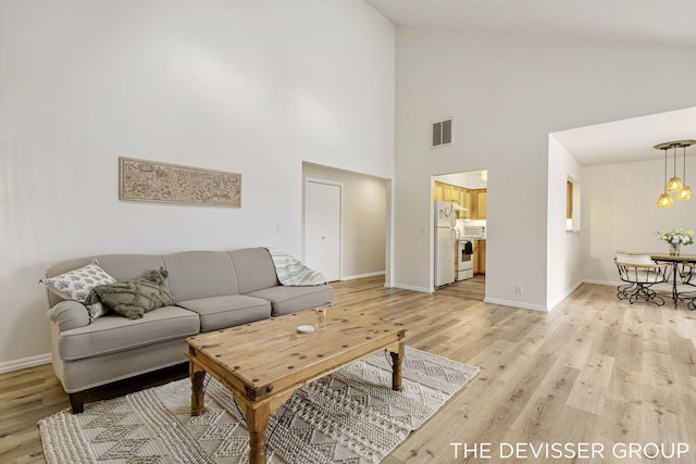 living room featuring lofted ceiling, a chandelier, and light hardwood / wood-style floors