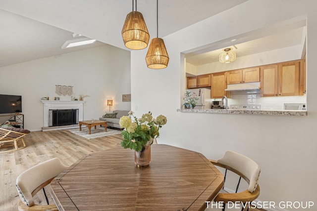 dining area featuring sink, light hardwood / wood-style flooring, and vaulted ceiling