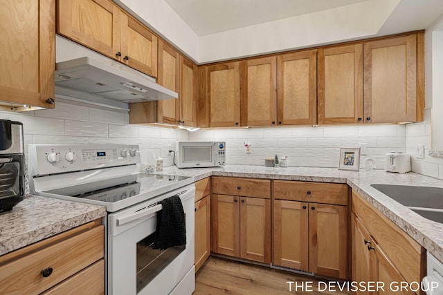 kitchen featuring sink, backsplash, white appliances, and light hardwood / wood-style floors