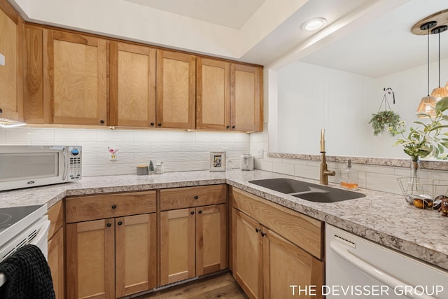 kitchen with sink, tasteful backsplash, wood-type flooring, decorative light fixtures, and white appliances