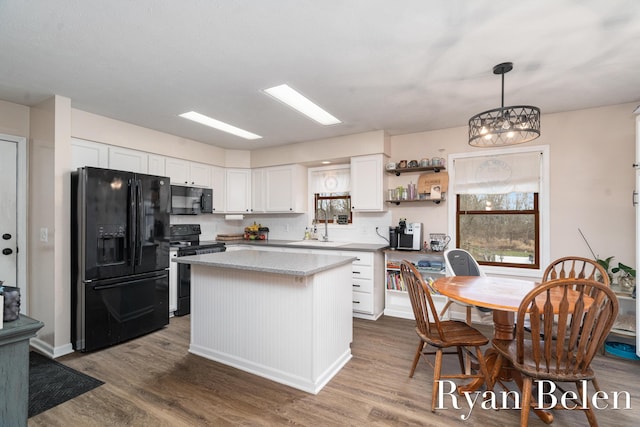 kitchen featuring white cabinets, a kitchen island, hanging light fixtures, and black appliances