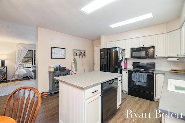 kitchen featuring black appliances, light hardwood / wood-style floors, white cabinets, a kitchen island, and decorative backsplash