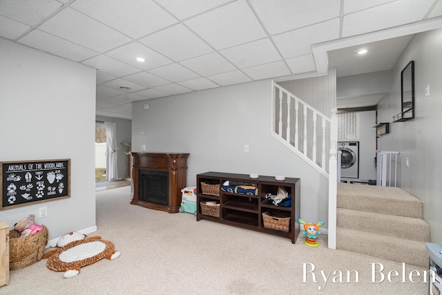 carpeted living room with a drop ceiling and washer / dryer