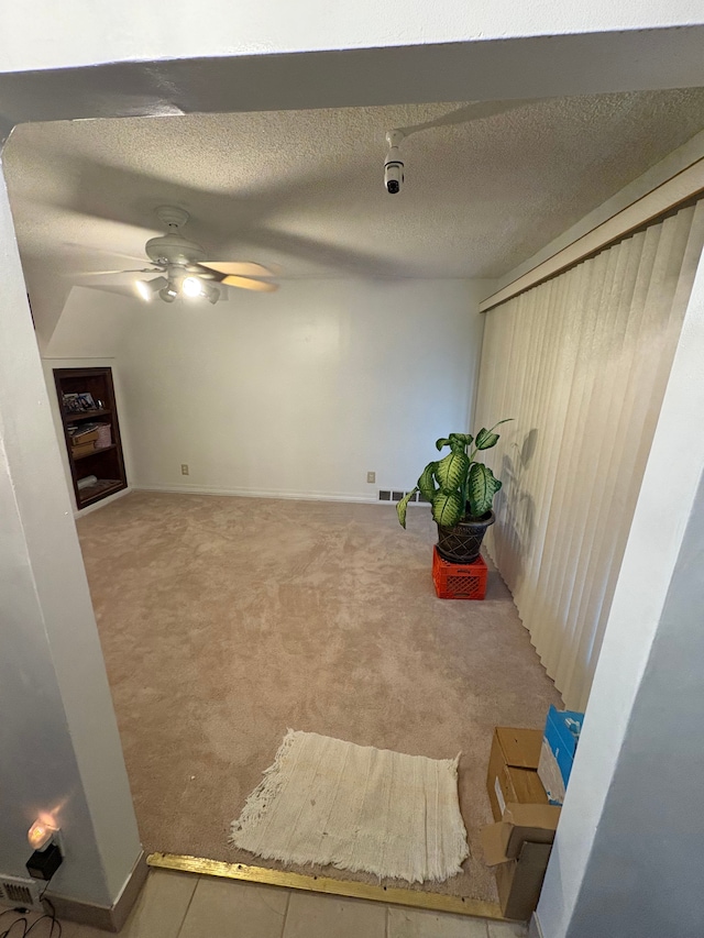 interior space with ceiling fan, light colored carpet, and a textured ceiling