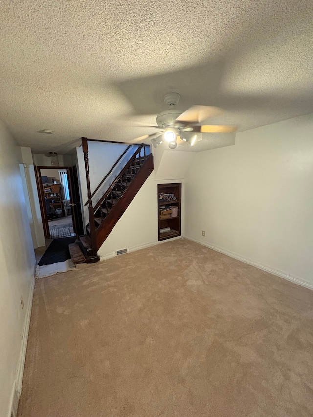 unfurnished living room featuring ceiling fan, carpet, and a textured ceiling