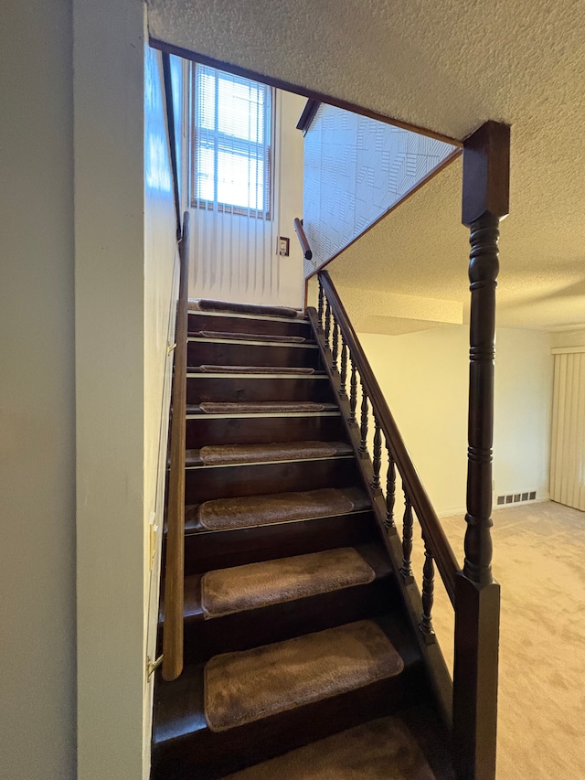 stairs featuring carpet floors and a textured ceiling