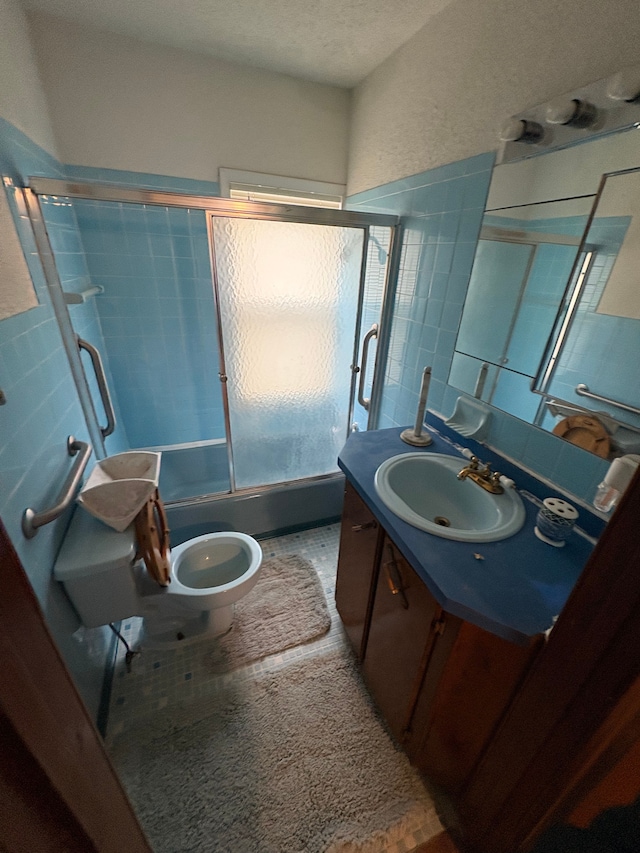 full bathroom with vanity, toilet, combined bath / shower with glass door, and tile walls