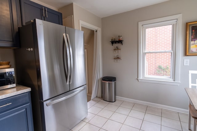 kitchen featuring light tile patterned floors, stainless steel refrigerator, and blue cabinets