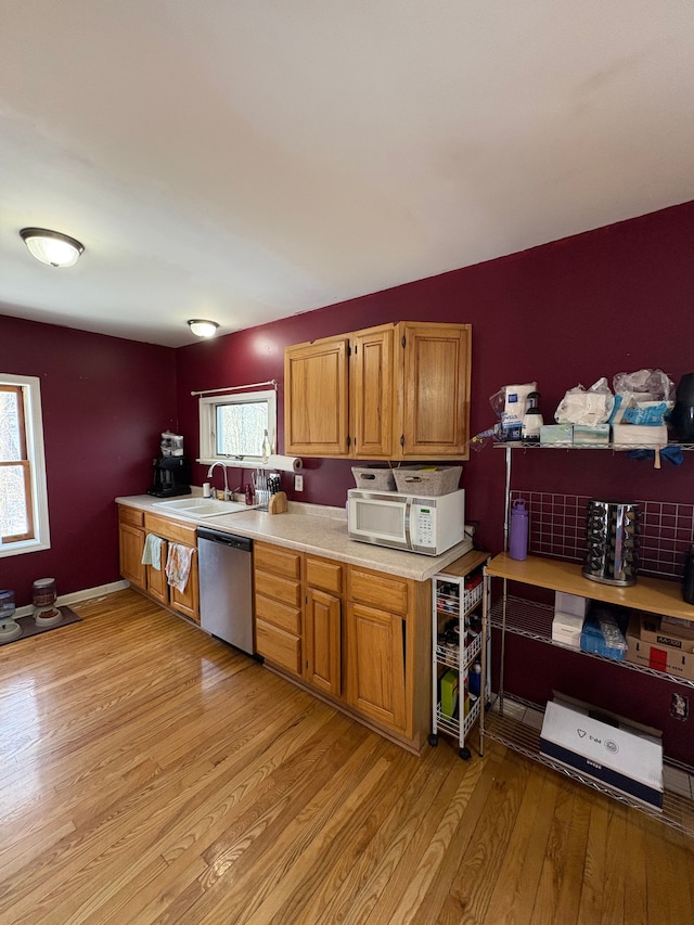 kitchen with stainless steel dishwasher, sink, and light hardwood / wood-style floors